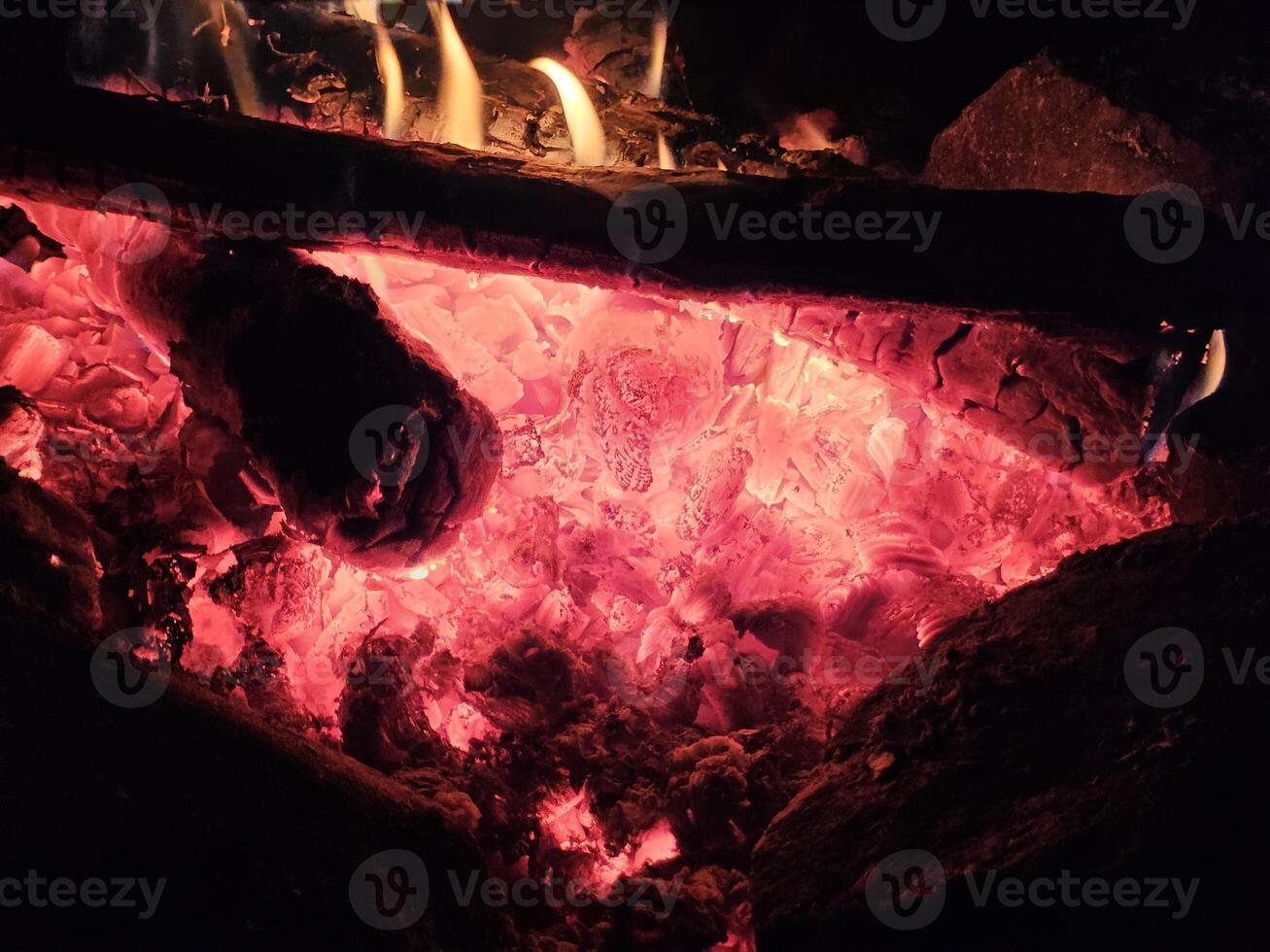 Flames of a stone pit fire at night in dark background at a campground