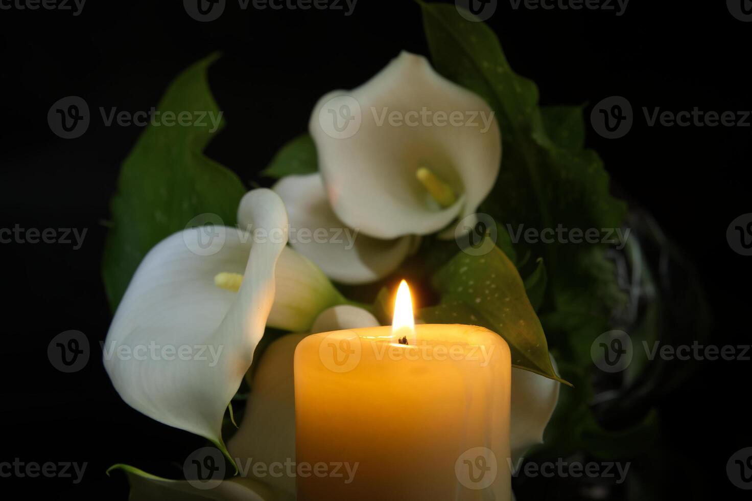 Burning wax candle in close up and white calla lily photo