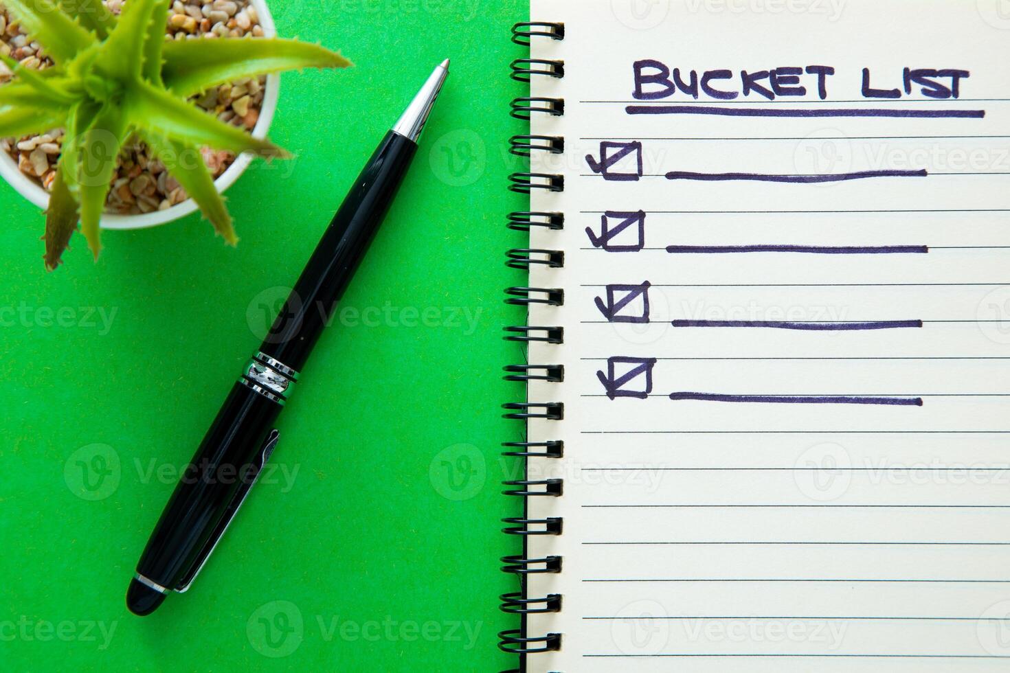 Bucket list on notebook with a pen. photo