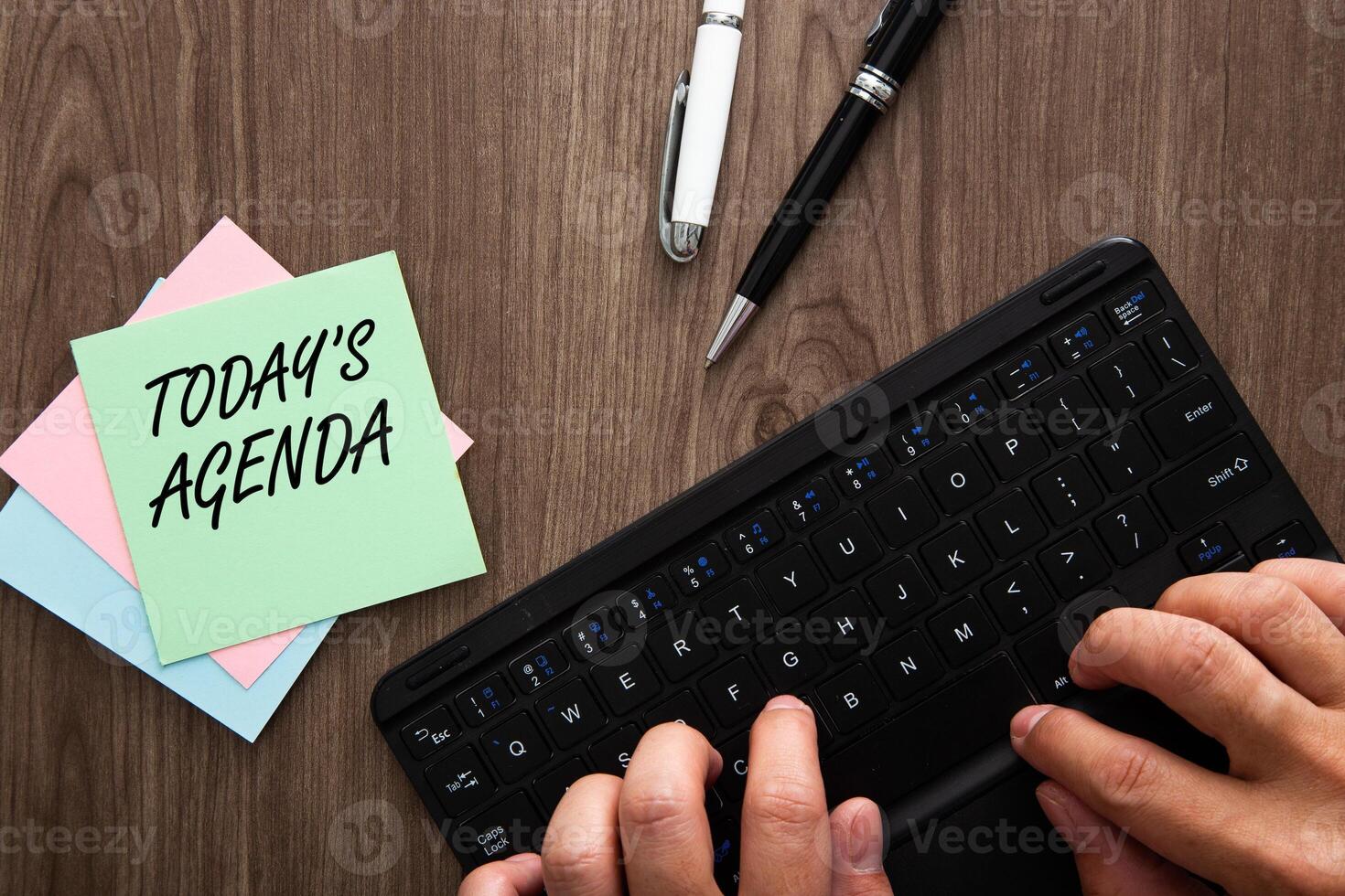 TODAYS AGENDA text with hand typing a keyboard and fountain pen on wooden background. Business and copy space concept photo