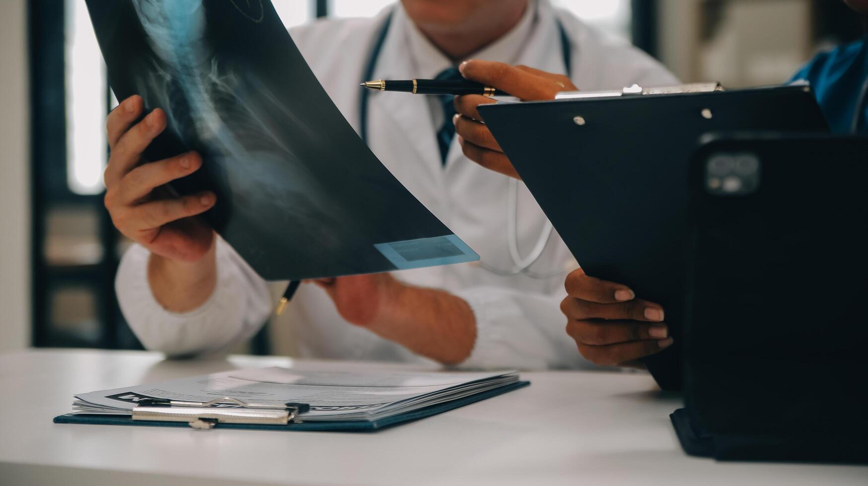 Focused mature male doctor and female nurse look at tablet screen discuss anamnesis together. Concentrated diverse medical professionals use pad device, engaged in team thinking in hospital. photo
