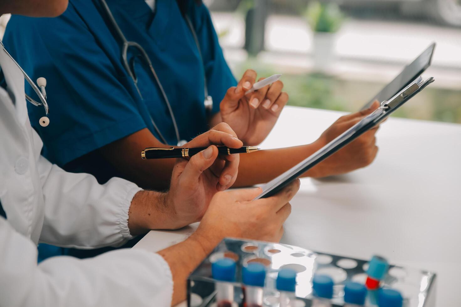 Medical worker in lab coat and sterile mask, doing a microscope analysis while her colleague are working behind photo