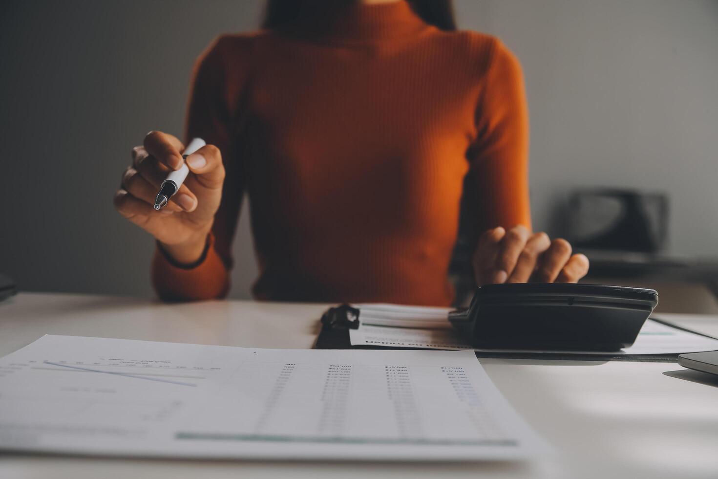 mujer de negocios asiática que usa una computadora portátil y trabaja en la oficina con un documento de calculadora en el escritorio, planificando el análisis del informe financiero, la inversión del plan de negocios, el concepto de análisis financiero. foto