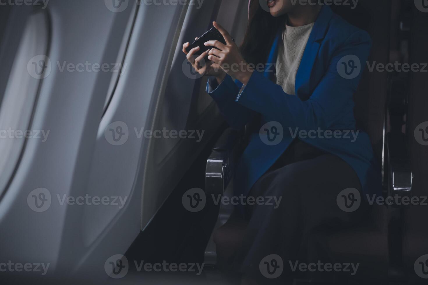 Young Asian business woman talking on smartphone, businesswoman working while flying at plane, Young woman using the internet at airplane, Air travel, long flight. photo