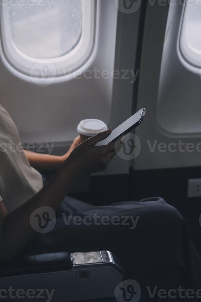 Asian woman enjoying enjoys a coffee comfortable flight while sitting in the airplane cabin, Passengers near the window. photo