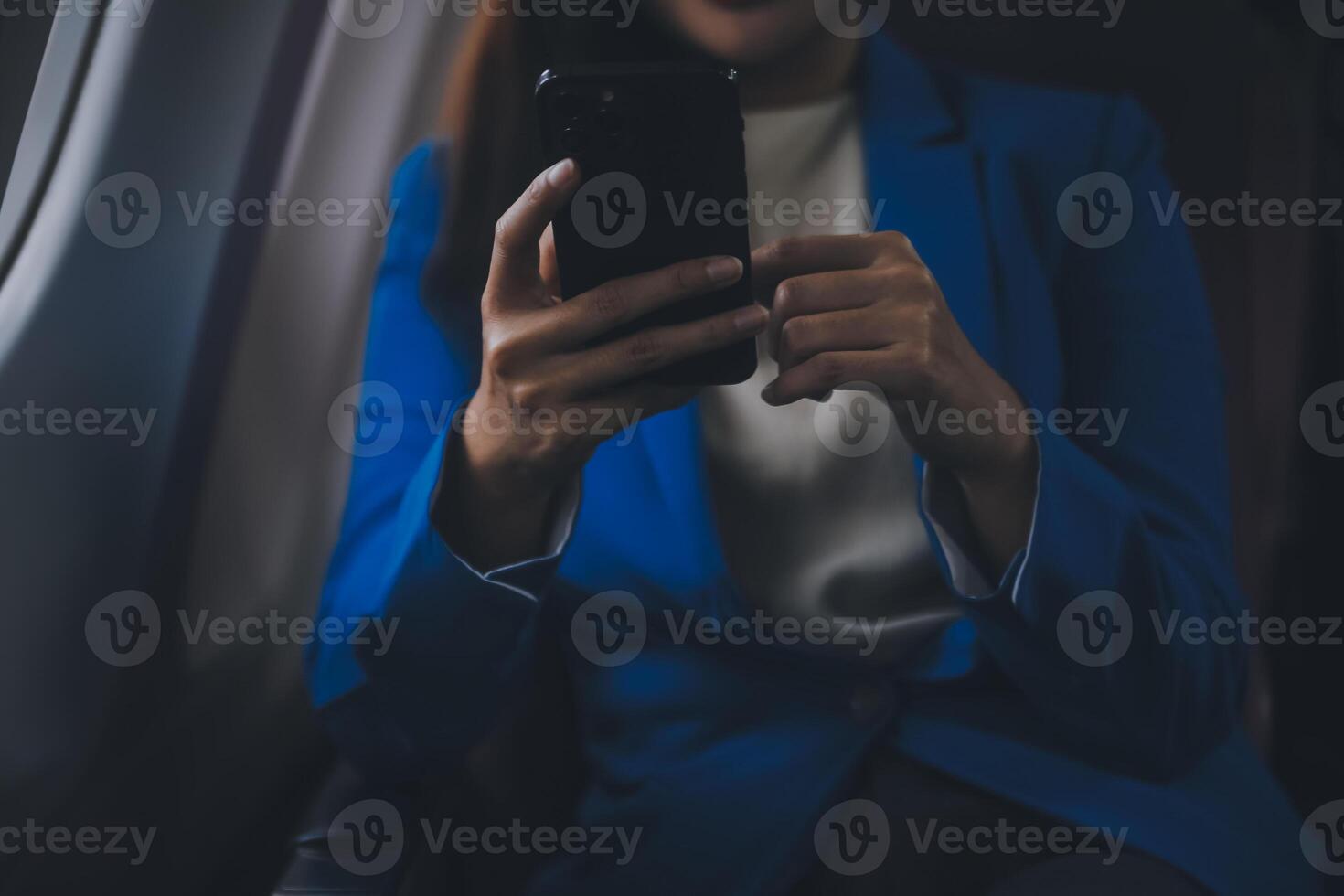 Young Asian business woman talking on smartphone, businesswoman working while flying at plane, Young woman using the internet at airplane, Air travel, long flight. photo