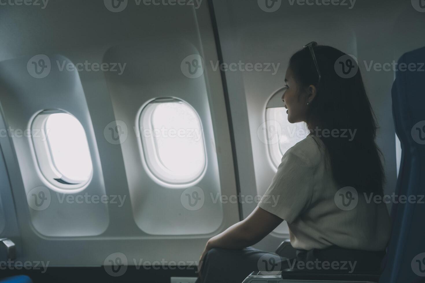 Silhouette of woman looks out the window of an flying airplane. Passenger on the plane resting beside the window. photo