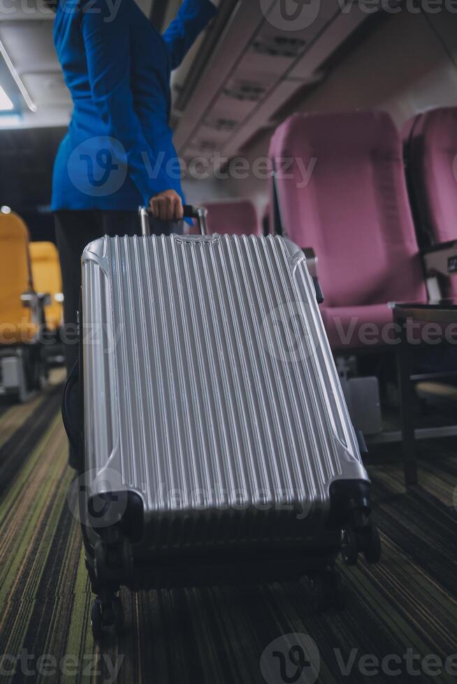 Asian female traveler putting luggage into overhead locker on airplane during boarding. photo