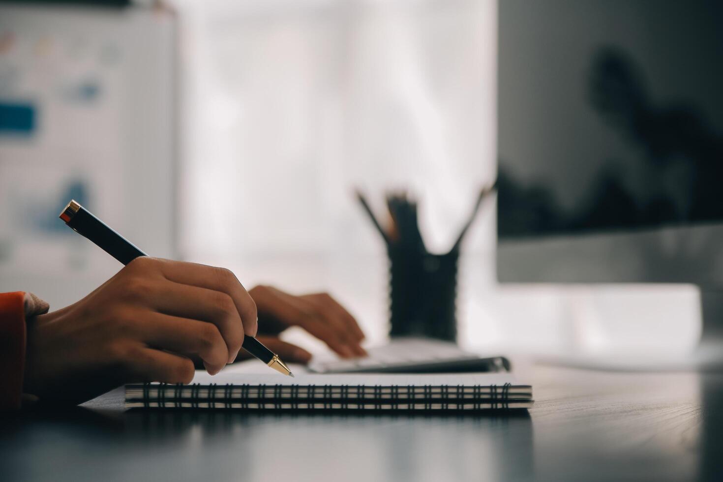 Asian Business woman using calculator and laptop for doing math finance on an office desk, tax, report, accounting, statistics, and analytical research concept photo