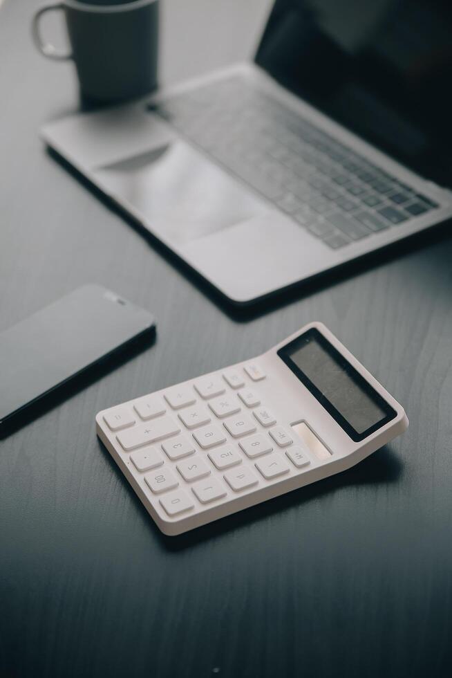 Asian Business woman using calculator and laptop for doing math finance on an office desk, tax, report, accounting, statistics, and analytical research concept photo