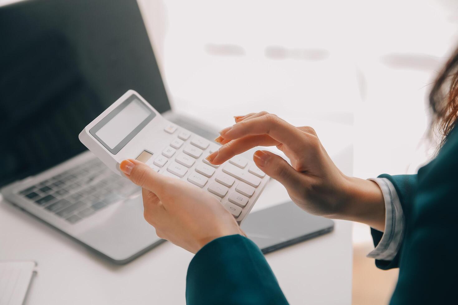 Businessman using a calculator to calculate numbers on a company's financial documents, he is analyzing historical financial data to plan how to grow the company. Financial concept. photo