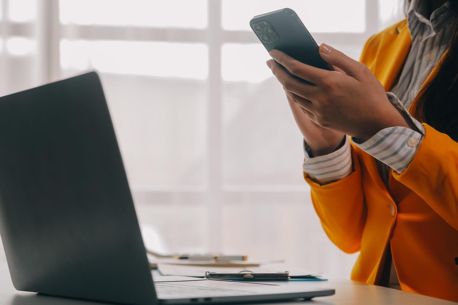 negocio mujer utilizando móvil teléfono durante trabajando en ordenador portátil computadora, surf el Internet, buscando negocio datos a moderno oficina. asiático mujer de negocios en línea trabajando en computadora a lugar de trabajo foto