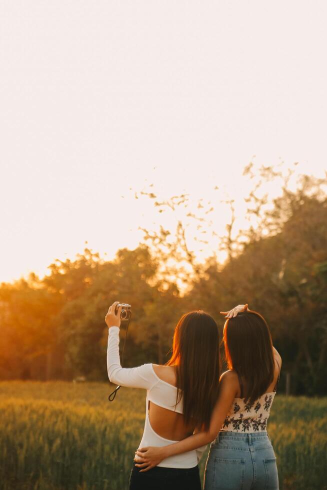 Young pretty woman in red summer dress and straw hat walking on yellow farm field with ripe golden wheat enjoying warm evening. photo