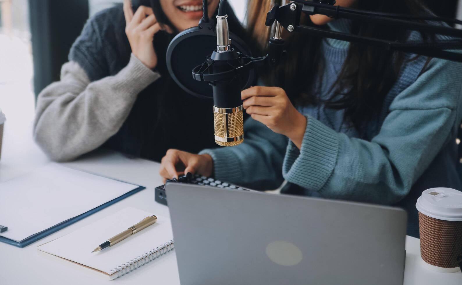 Woman recording a podcast on her laptop computer with headphones and a microscope. Female podcaster making audio podcast from her home studio. photo