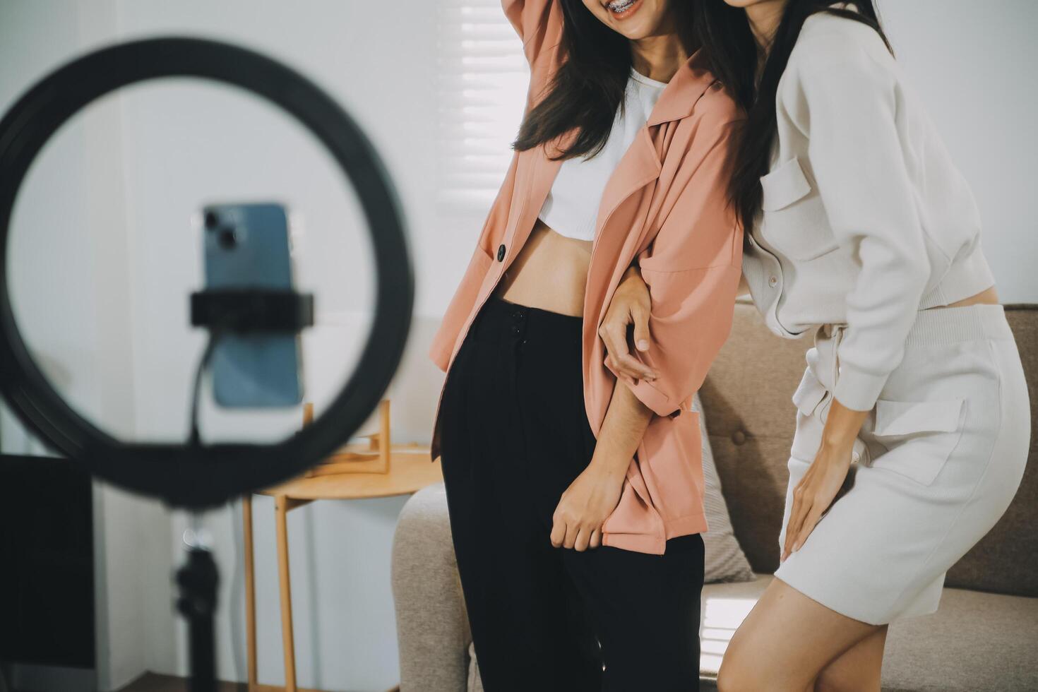 asiático joven mujer con su amigo Tiktoker creado su bailando vídeo por teléfono inteligente cámara juntos. a compartir vídeo en social medios de comunicación solicitud foto