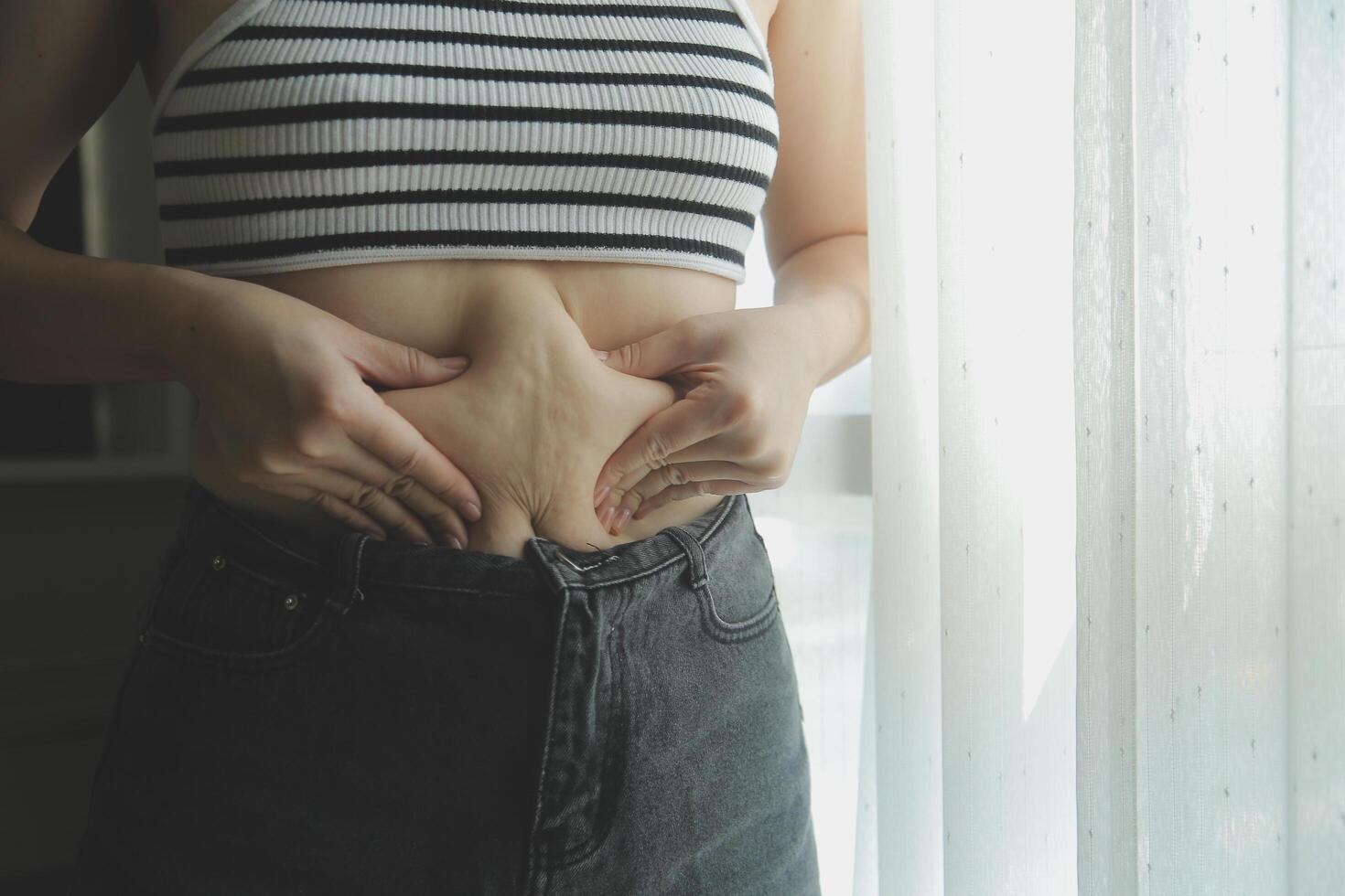 mujer cuerpo grasa barriga. obeso mujer mano participación excesivo barriga gordo. dieta estilo de vida concepto a reducir barriga y forma arriba sano estómago músculo. foto