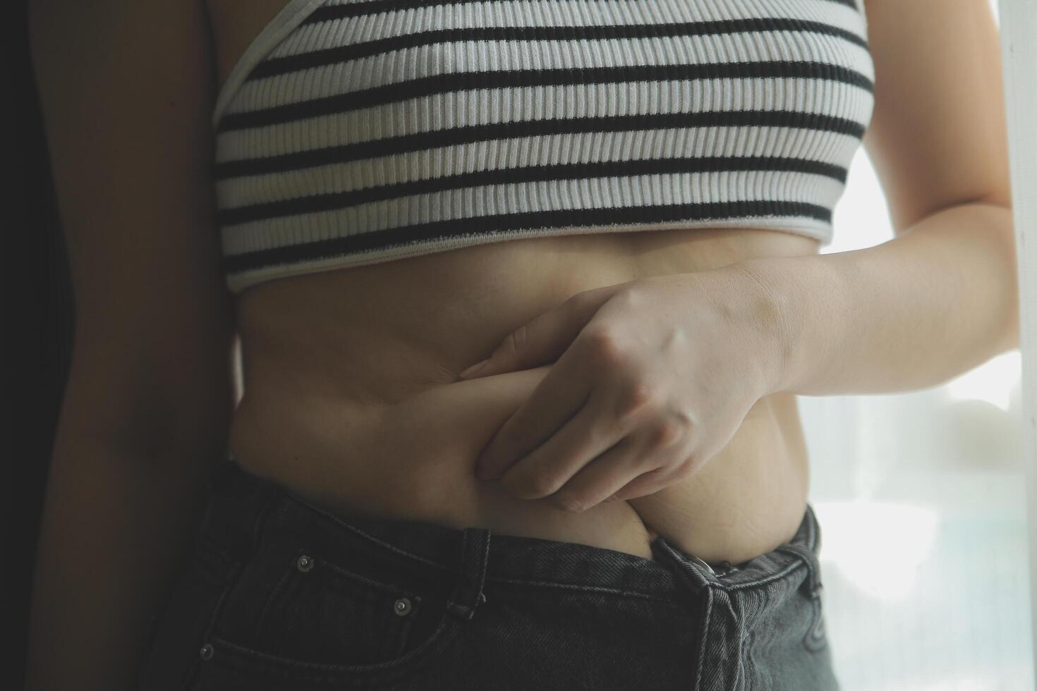 Women body fat belly. Obese woman hand holding excessive belly fat. diet lifestyle concept to reduce belly and shape up healthy stomach muscle. photo