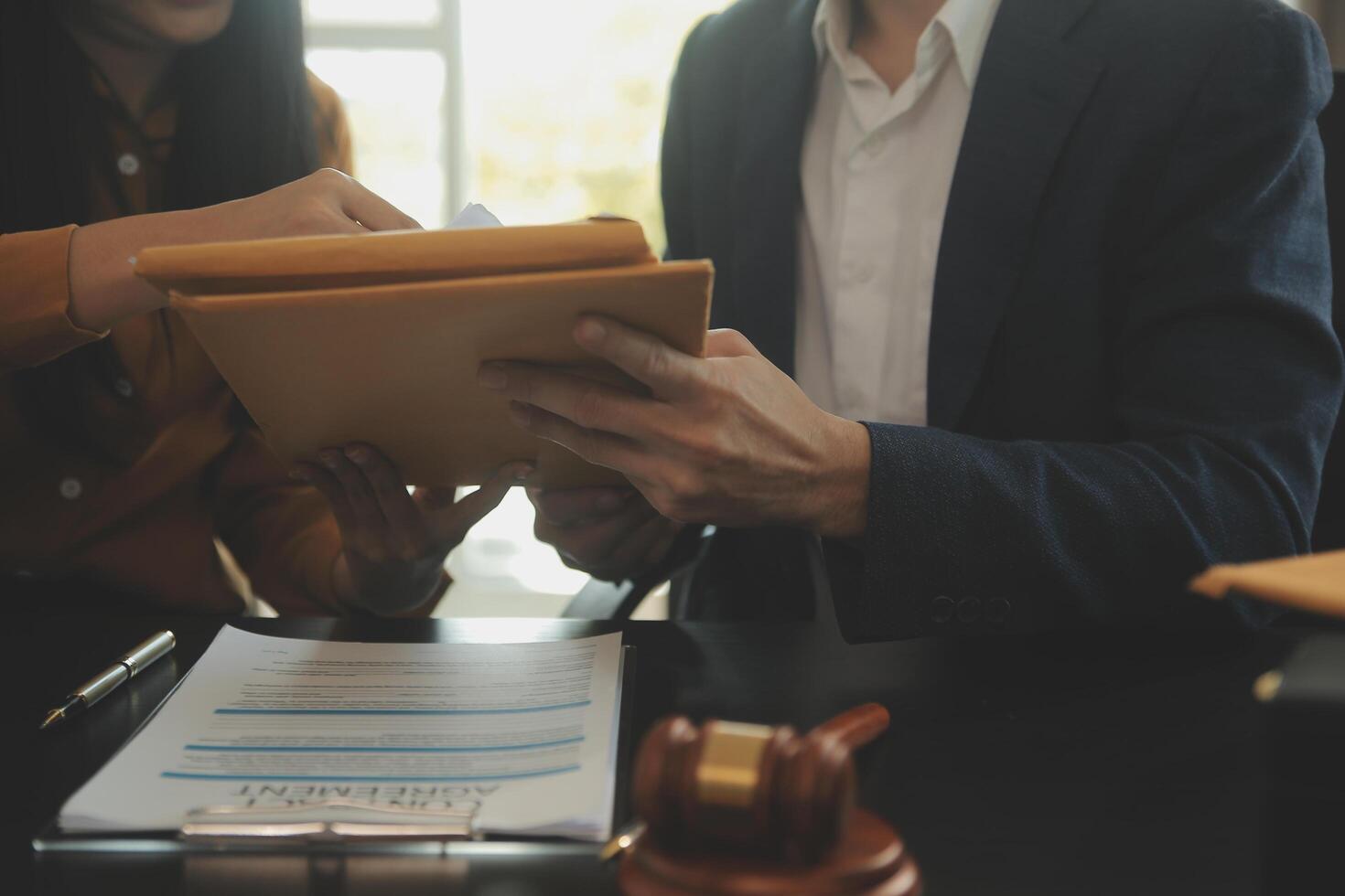 Justice and Law concept. Legal counsel presents to the client a signed contract with gavel and legal law or legal having team meeting at law firm in background photo