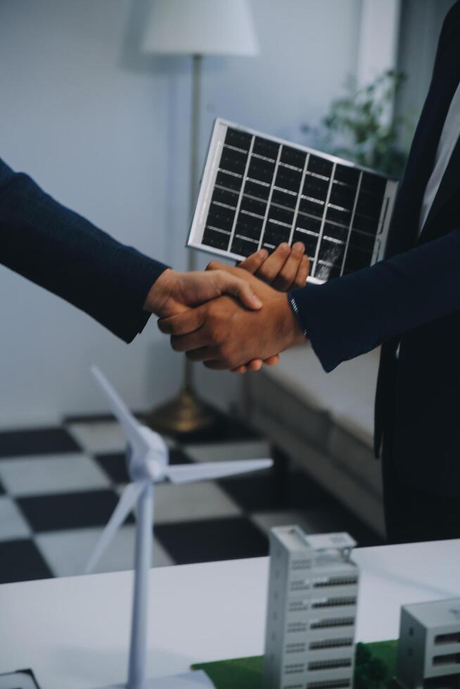 dos joven ingenieros pericia en solar célula instalación reuniones y discusión en el trabajo. planificación a Instalar en pc solar fotovoltaica paneles en techo parte superior en el oficina habitación con fábrica edificio plan. foto