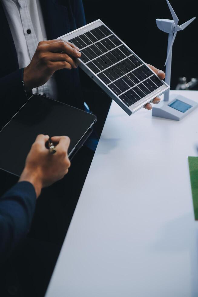 Two Young Engineers Expertise in Solar Cell Installation Meetings and Discussion in The Job. Planning to Install Solar Photovoltaic Panels on Roof Top in The Office Room with Factory Building Plan. photo