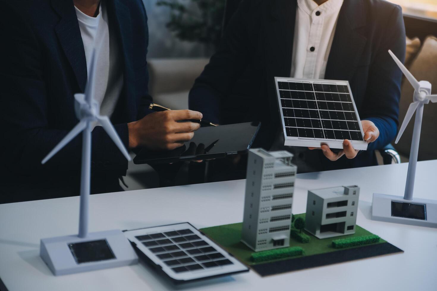 dos joven ingenieros pericia en solar célula instalación reuniones y discusión en el trabajo. planificación a Instalar en pc solar fotovoltaica paneles en techo parte superior en el oficina habitación con fábrica edificio plan. foto