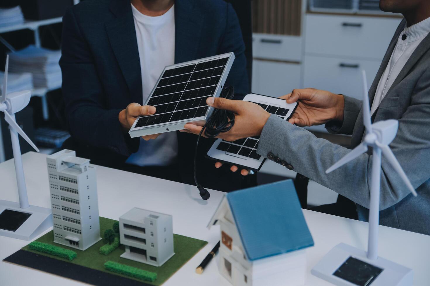 Two Young Engineers Expertise in Solar Cell Installation Meetings and Discussion in The Job. Planning to Install Solar Photovoltaic Panels on Roof Top in The Office Room with Factory Building Plan. photo
