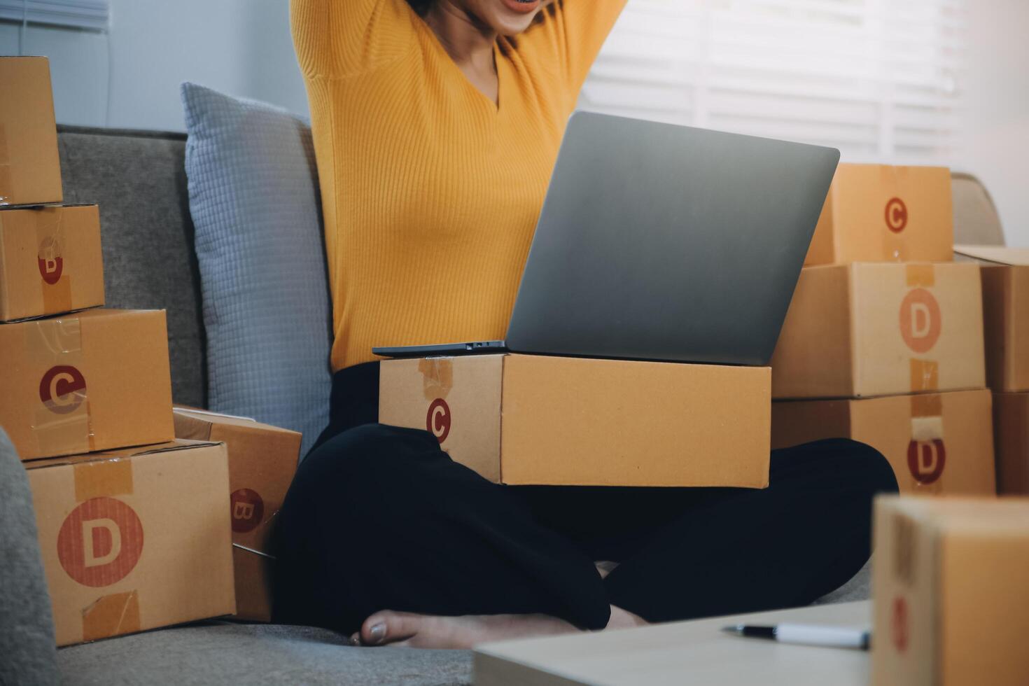 Startup small business entrepreneur or freelance Asian woman using a laptop with box, Young success Asian woman with her hand lift up, online marketing packaging box and delivery, SME concept. photo