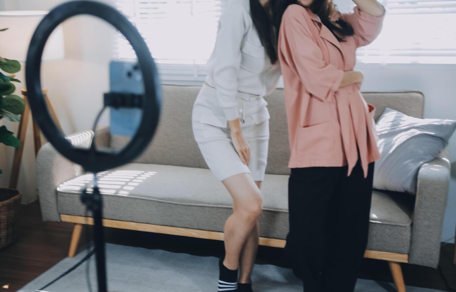 asiático joven mujer con su amigo Tiktoker creado su bailando vídeo por teléfono inteligente cámara juntos. a compartir vídeo en social medios de comunicación solicitud foto