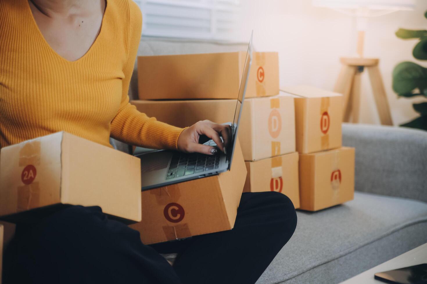 Startup small business entrepreneur or freelance Asian woman using a laptop with box, Young success Asian woman with her hand lift up, online marketing packaging box and delivery, SME concept. photo