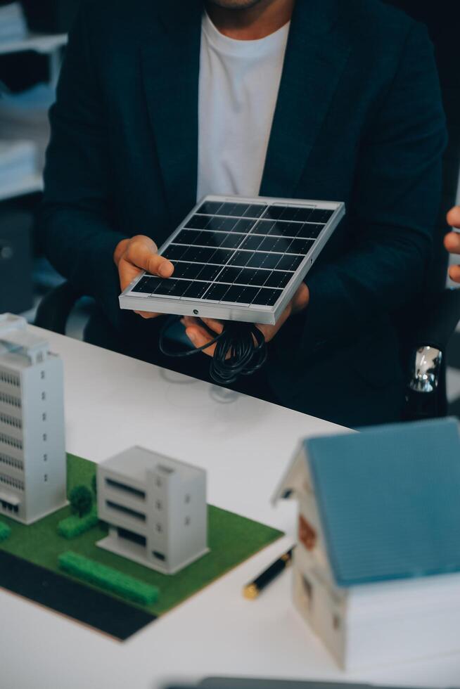 dos joven ingenieros pericia en solar célula instalación reuniones y discusión en el trabajo. planificación a Instalar en pc solar fotovoltaica paneles en techo parte superior en el oficina habitación con fábrica edificio plan. foto