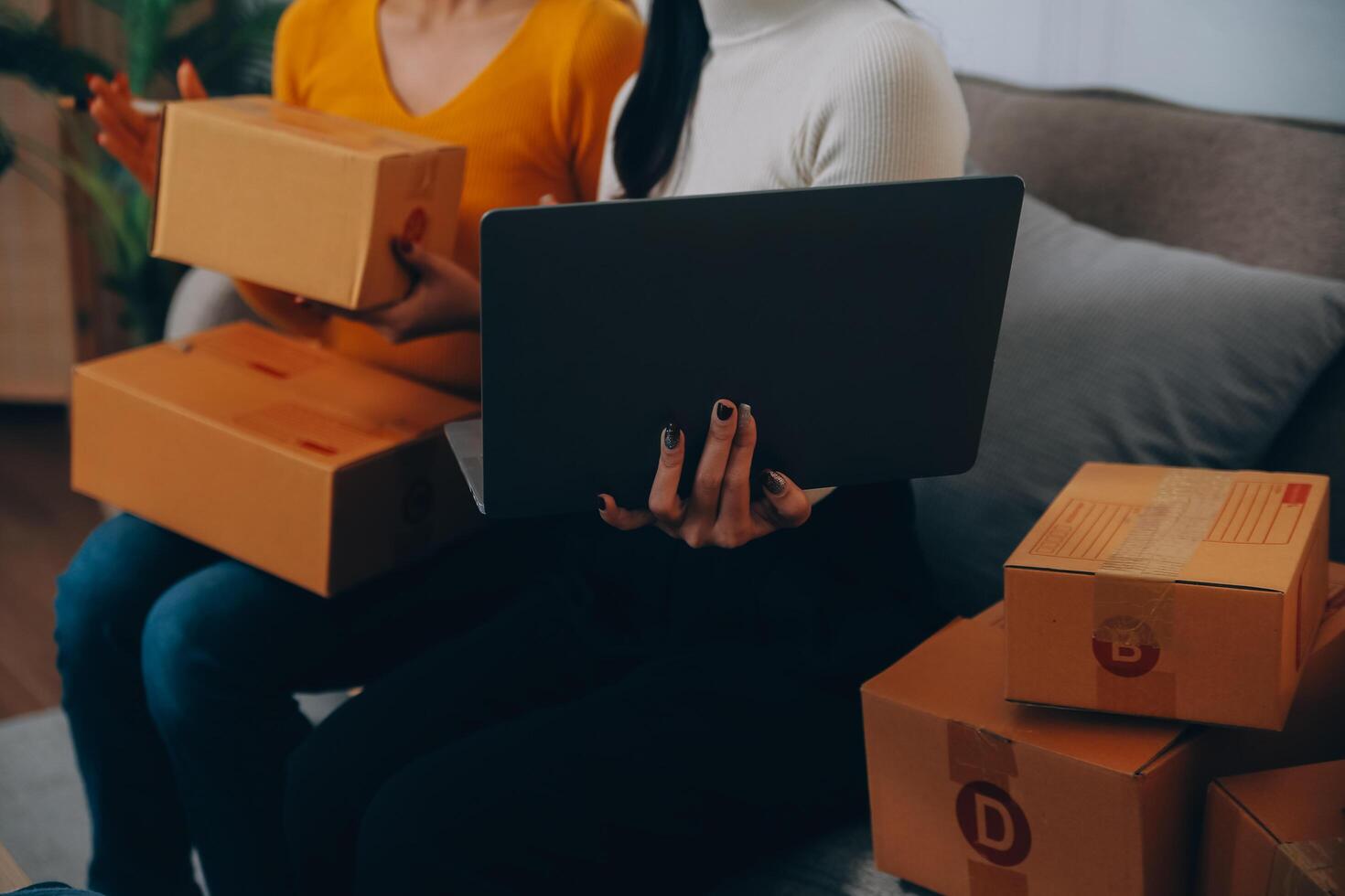 Asian SME business women use laptop computer checking customer order online shipping boxes at home. Starting Small business entrepreneur SME freelance. Online business, Work at home concept. photo