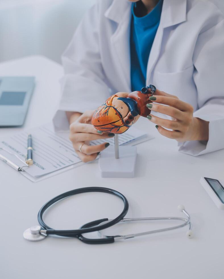 Doctor explaining heart to elderly patient. Doctor explaining the heart model. Doctors pen point to a model of the heart photo