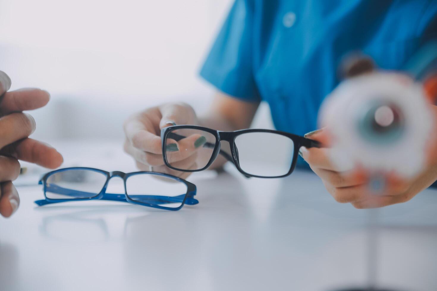 Close-up of Asian female doctor talking with elderly patient showing eyeball model and explaining eye disease in hospital photo