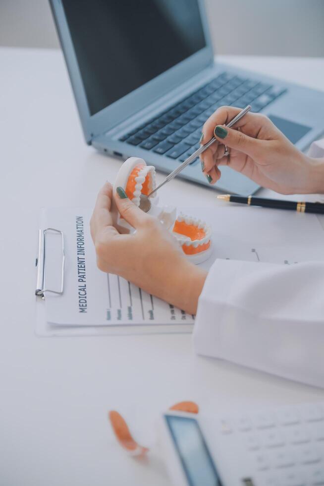 los dentistas están discutiendo problemas dentales al informar la imagen de rayos X en la pantalla del portátil a los pacientes. foto