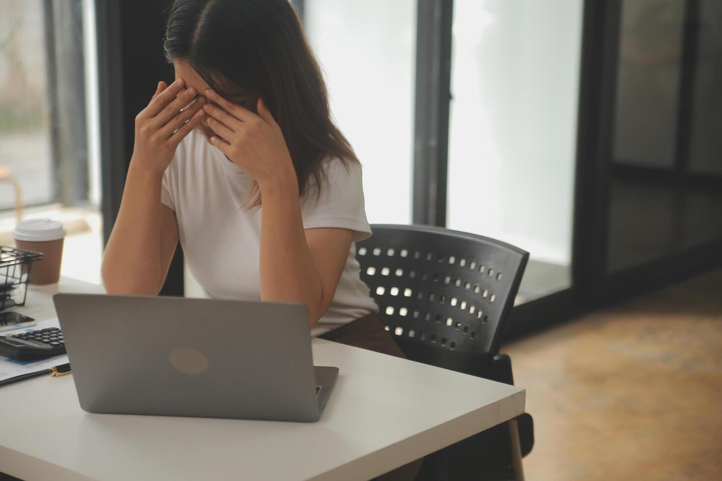 cansado negocio mujer soñoliento y aburrido desde sentado a un escritorio para un largo hora y tiene oficina síndrome foto