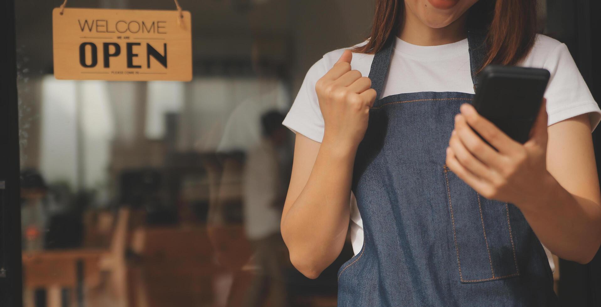 Startup successful small business owner sme beauty girl stand with tablet smartphone in coffee shop restaurant. Portrait of asian tan woman barista cafe owner. SME entrepreneur seller business concept photo