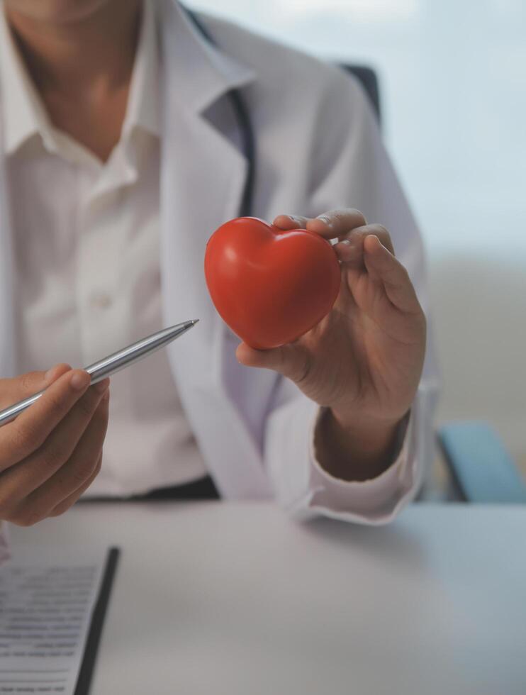 manos de médico mujer participación rojo corazón, demostración símbolo de amar, humano apoyo a paciente, promoviendo médico seguro, temprano chequeo para cuidado de la salud, cardiólogo ayuda. cerca arriba de objeto foto