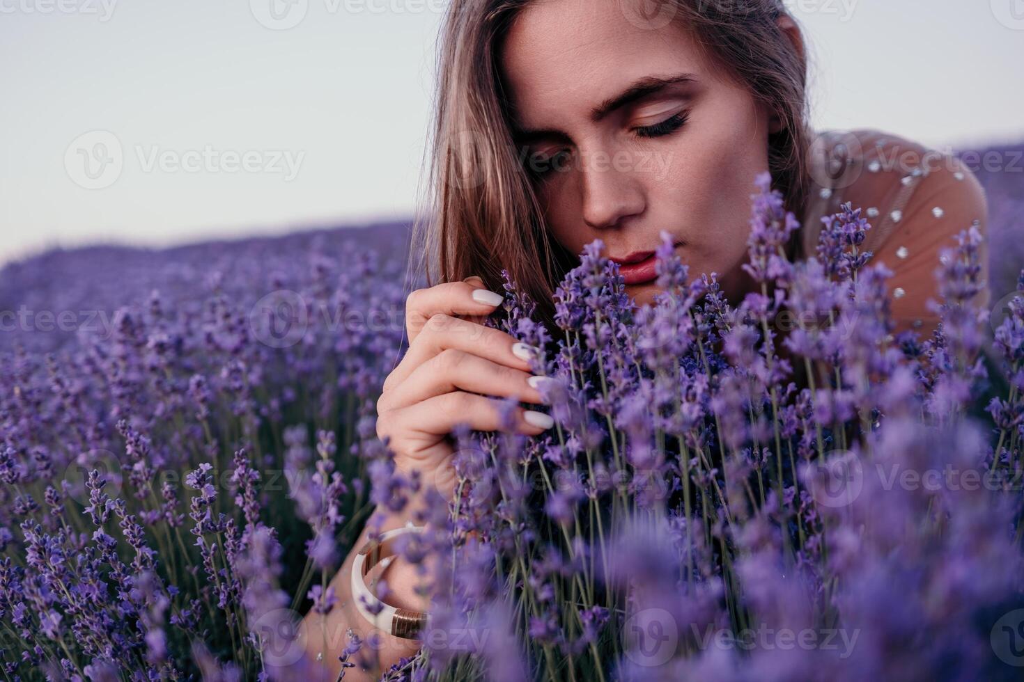 Woman lavender field. Happy carefree woman in beige dress and hat with large brim smelling a blooming lavender on sunset. Perfect for inspirational and warm concepts in travel and wanderlust. Close up photo