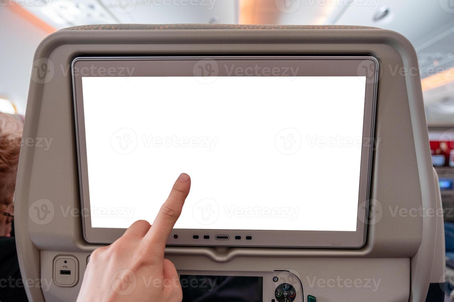 Hand touching on white display screen with joystick on rear seat in airplane photo