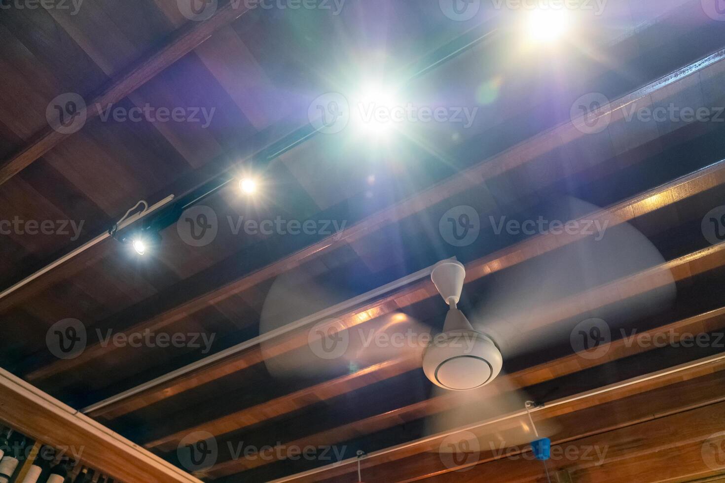 Ancient rotation fan on wood ceiling with light shining decoration photo
