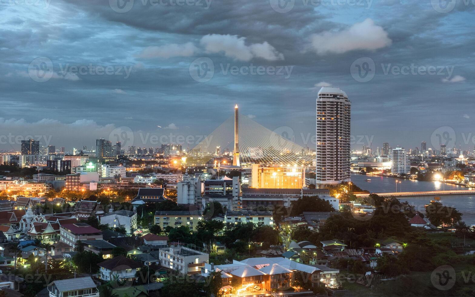 Cityscape of Rama 8 bridge over the Chaophraya river with buildings glowing at dusk photo