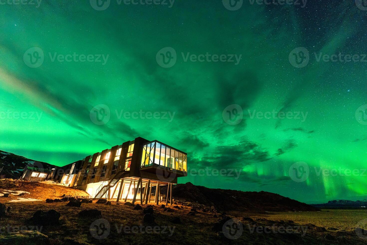 Aurora borealis, Northern lights glowing over luxury hotel on volcanic wilderness in winter at Iceland photo