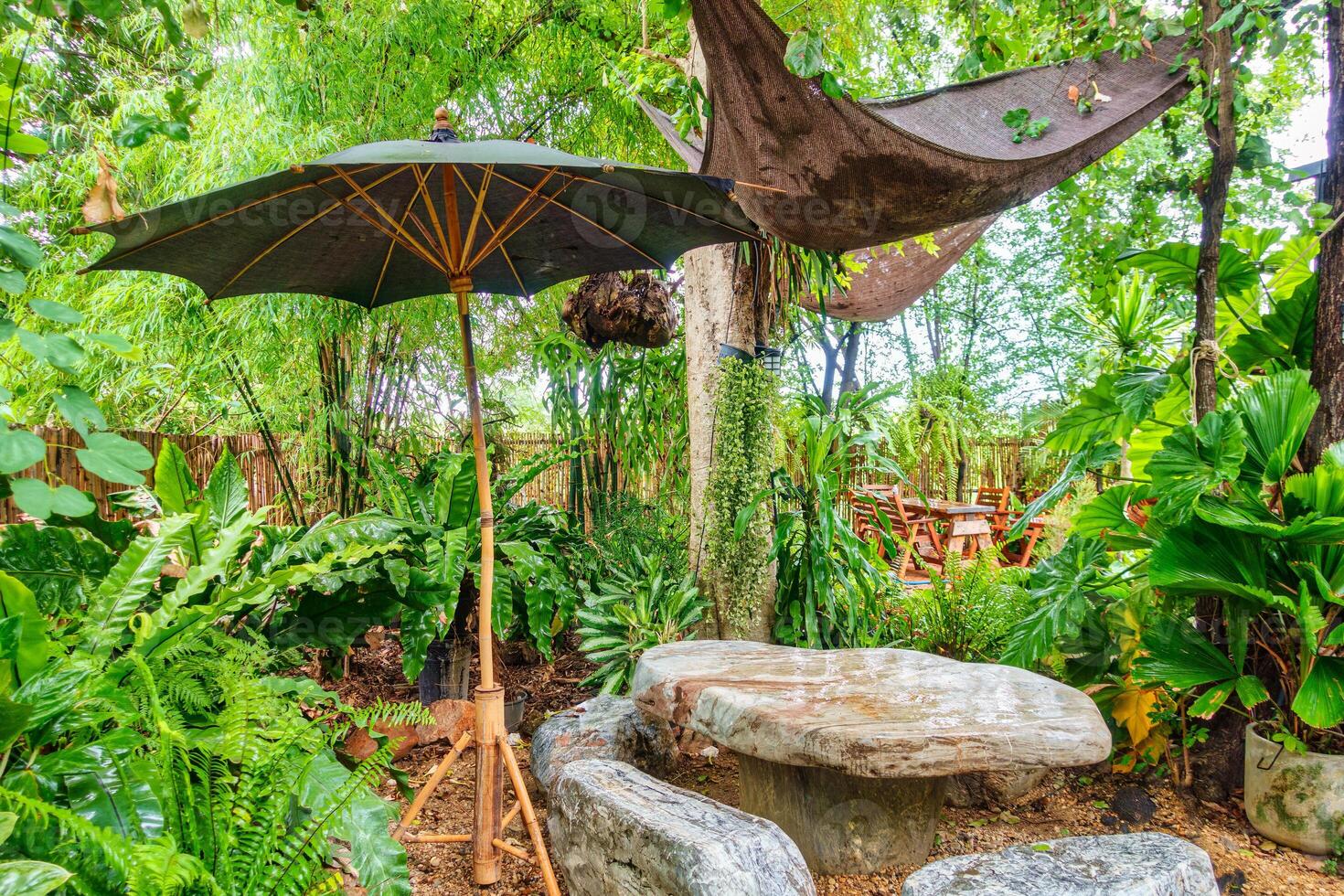 Natural rock table, seat and parasol in tropical garden on backyard photo