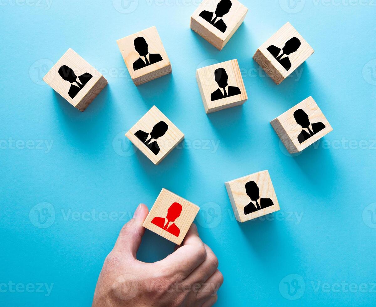 Employment choice concept. Hand choosing a wooden person block from a set. photo