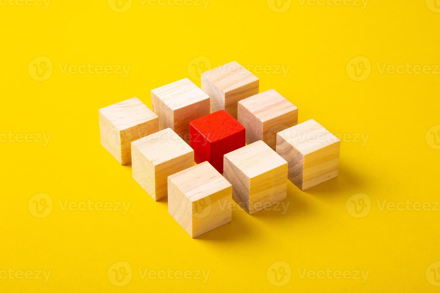 Red wooden block standing out from the group wooden blocks on yellow background. Leadership and divergent views concepts photo