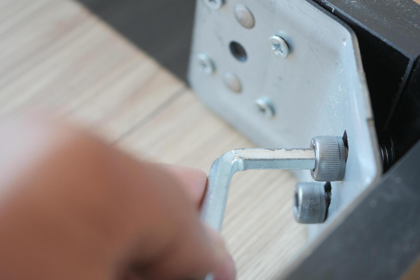 Using a wrench, theyre removing a screw from metal photo