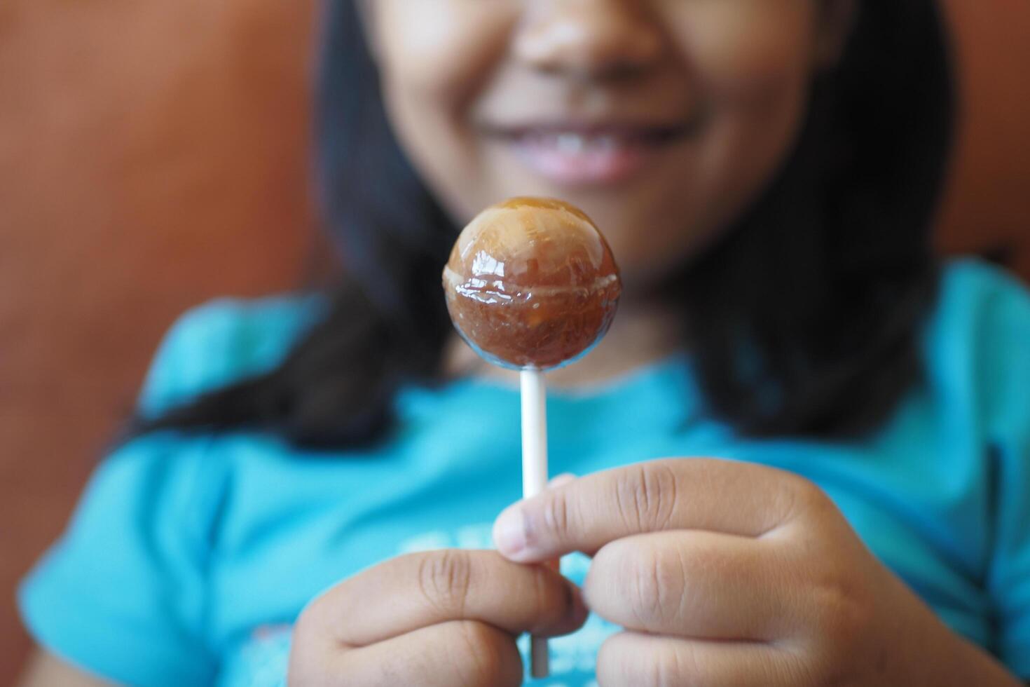 child is licking colorful candy on stick, photo