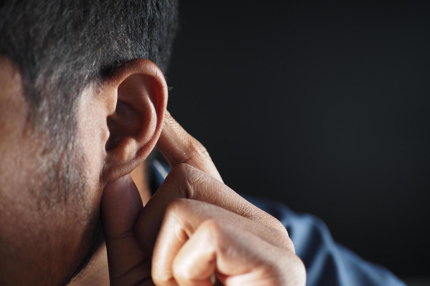 young man having ear pain touching his painful ear , photo