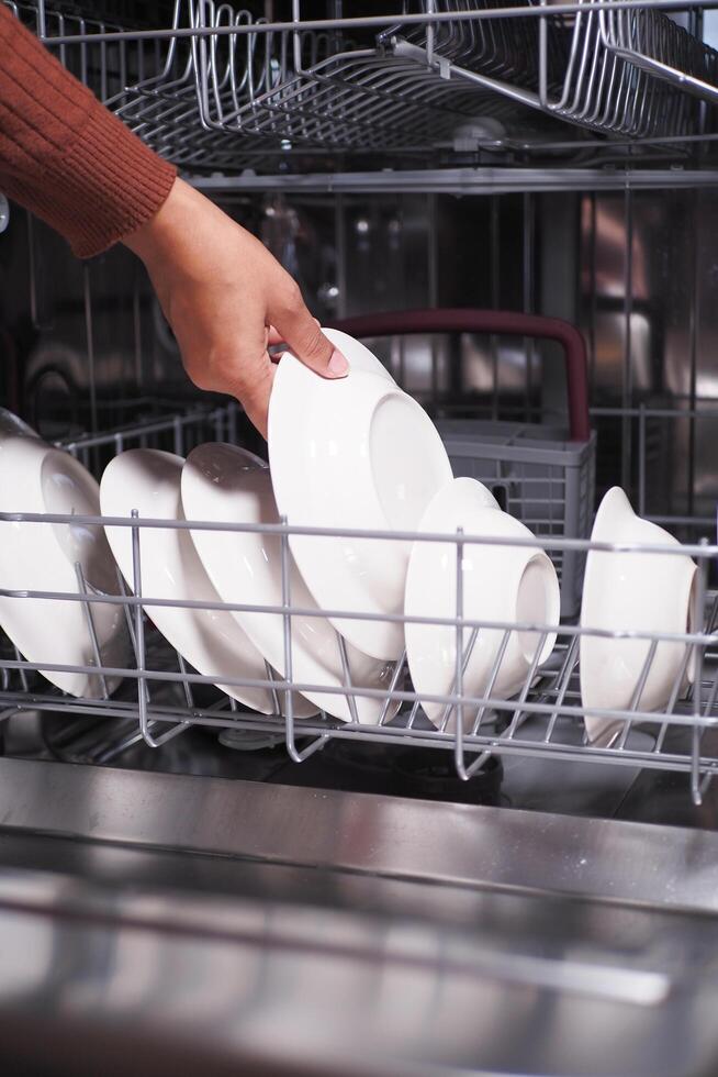A young woman opens takes out clean white plate. photo