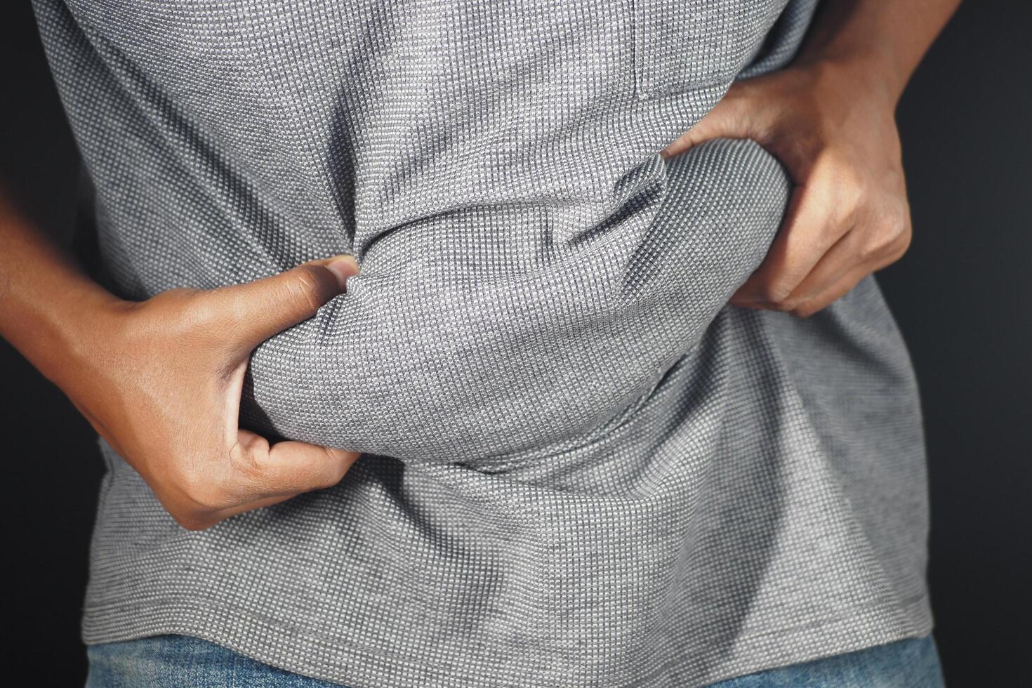 man's hand holding excessive belly fat, overweight concept photo